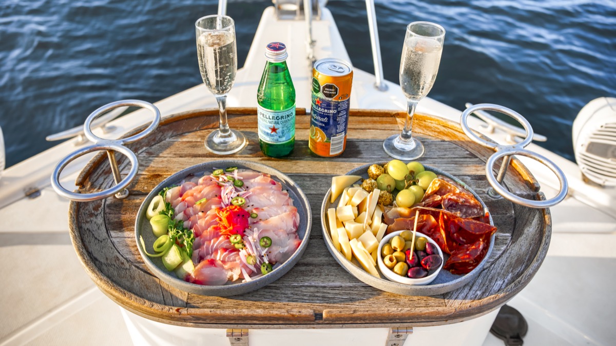 Fresh ceviche and charcuterie board with champagne on the bow