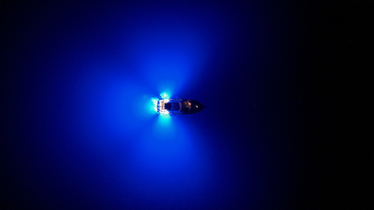 Yacht at night with underwater blue lights in the open ocean